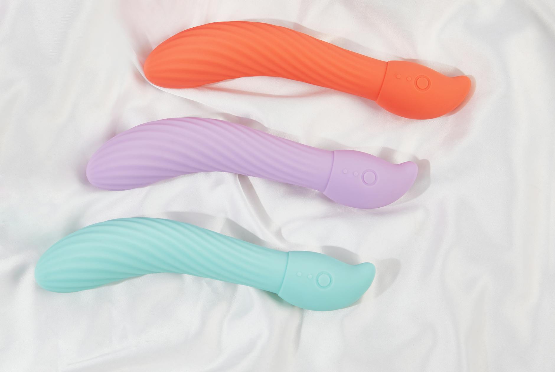 Woman holding pink and blue silicone vibrators thoughtfully