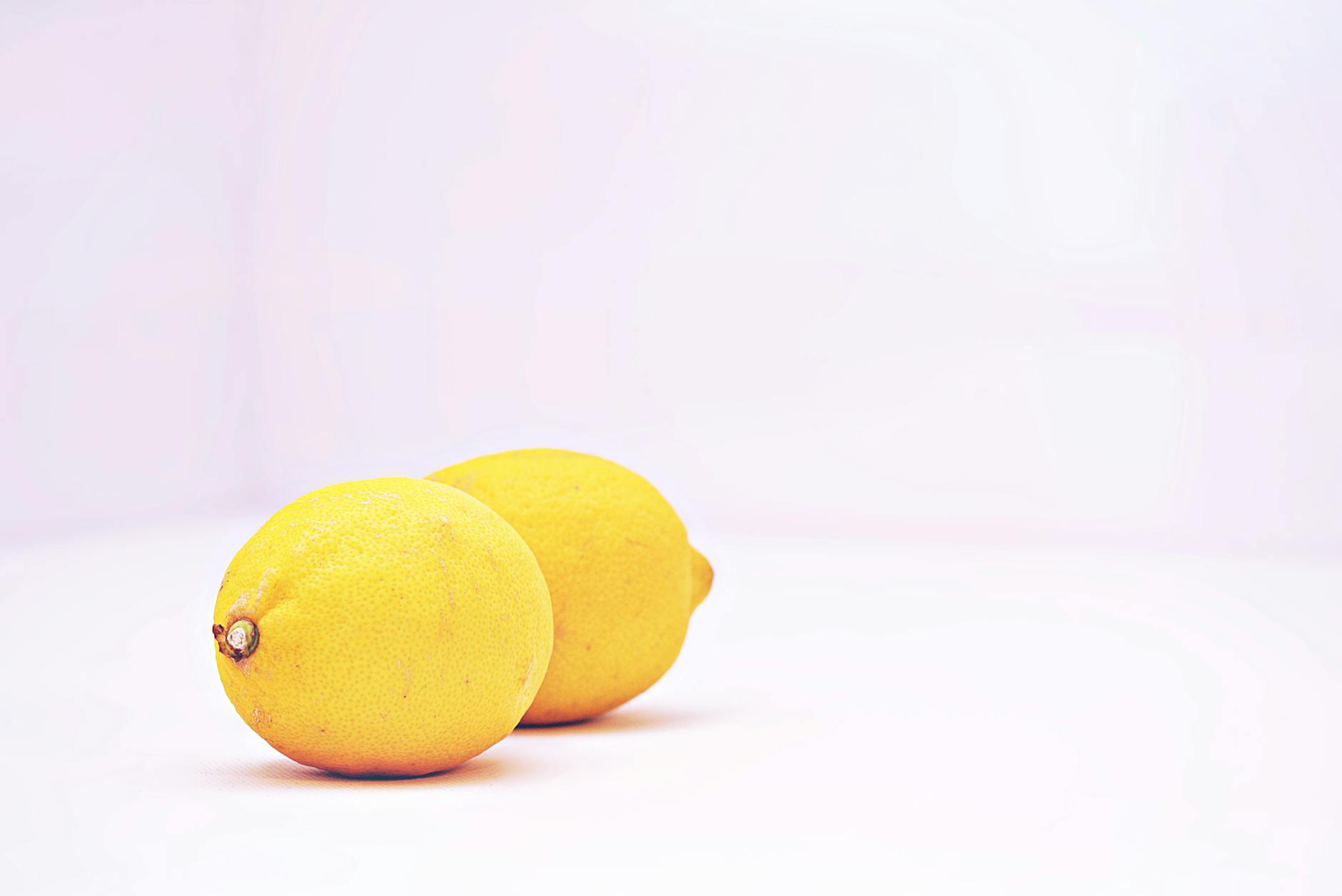 A close-up of a hand holding an orange vibrator against a minimalistic purple backdrop, showcasing modern sensuality.