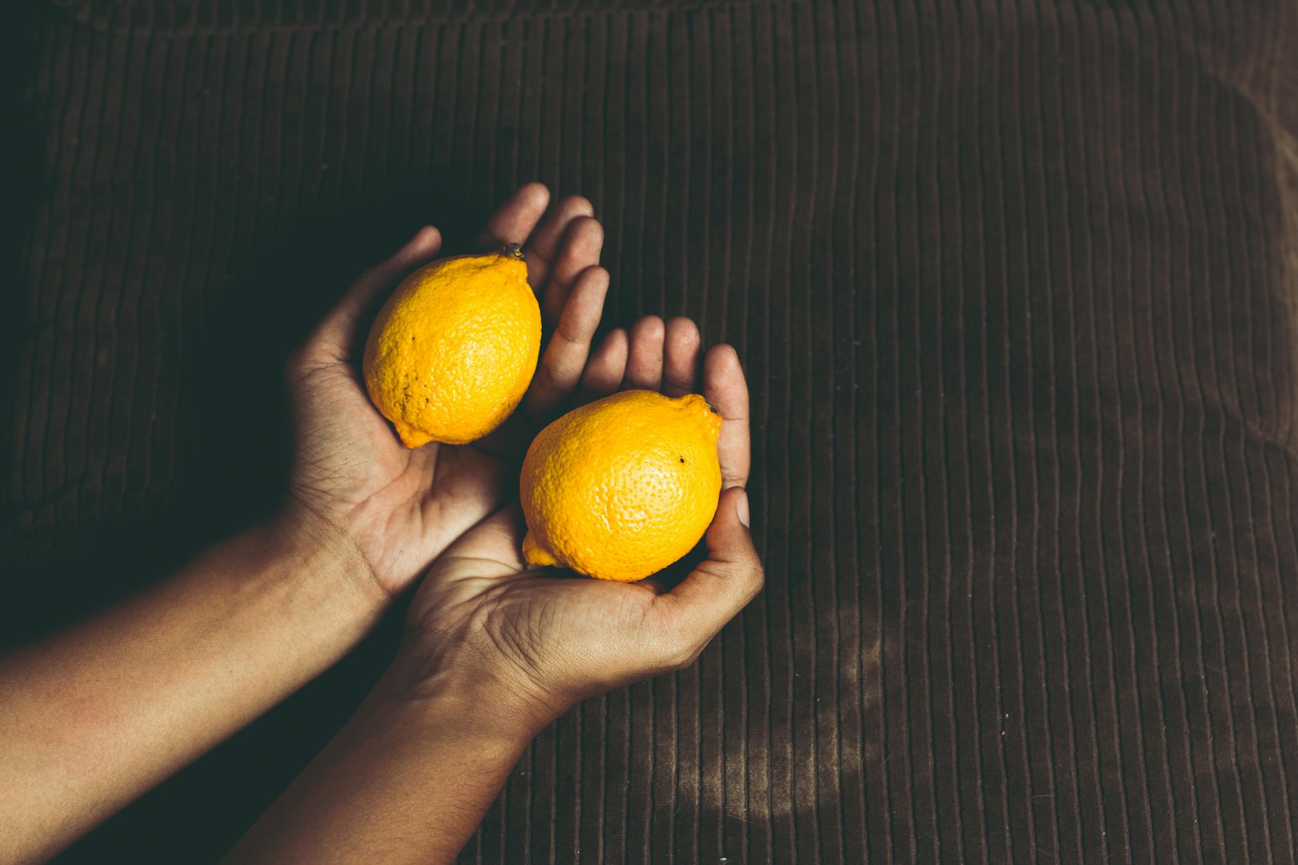 Two fresh lemons held in cupped hands, symbolizing the citrus-inspired design of the lemon vibrator