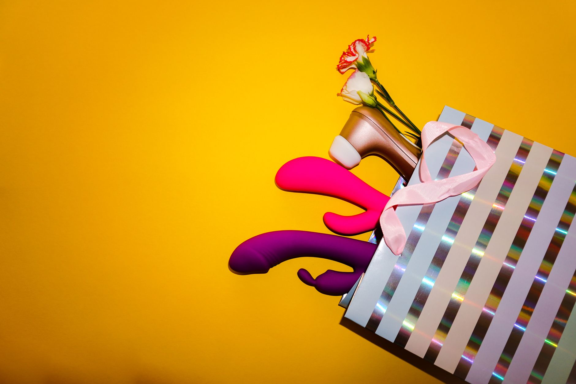 A hand holding a lemon-colored clitoral vibrator against a soft purple backdrop, representing gentle postpartum intimacy.