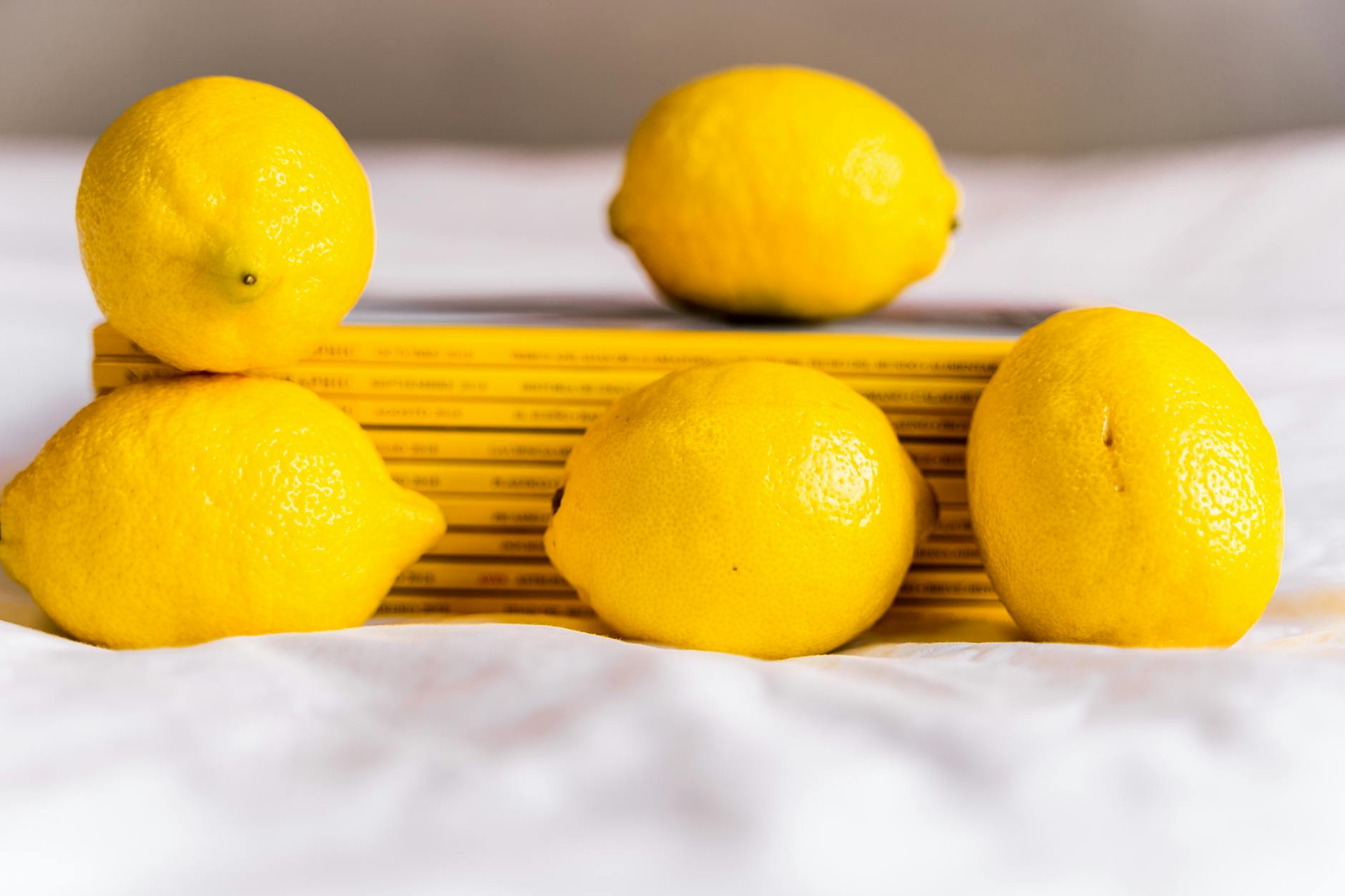 Fresh yellow lemons arranged on a white surface with stacked books